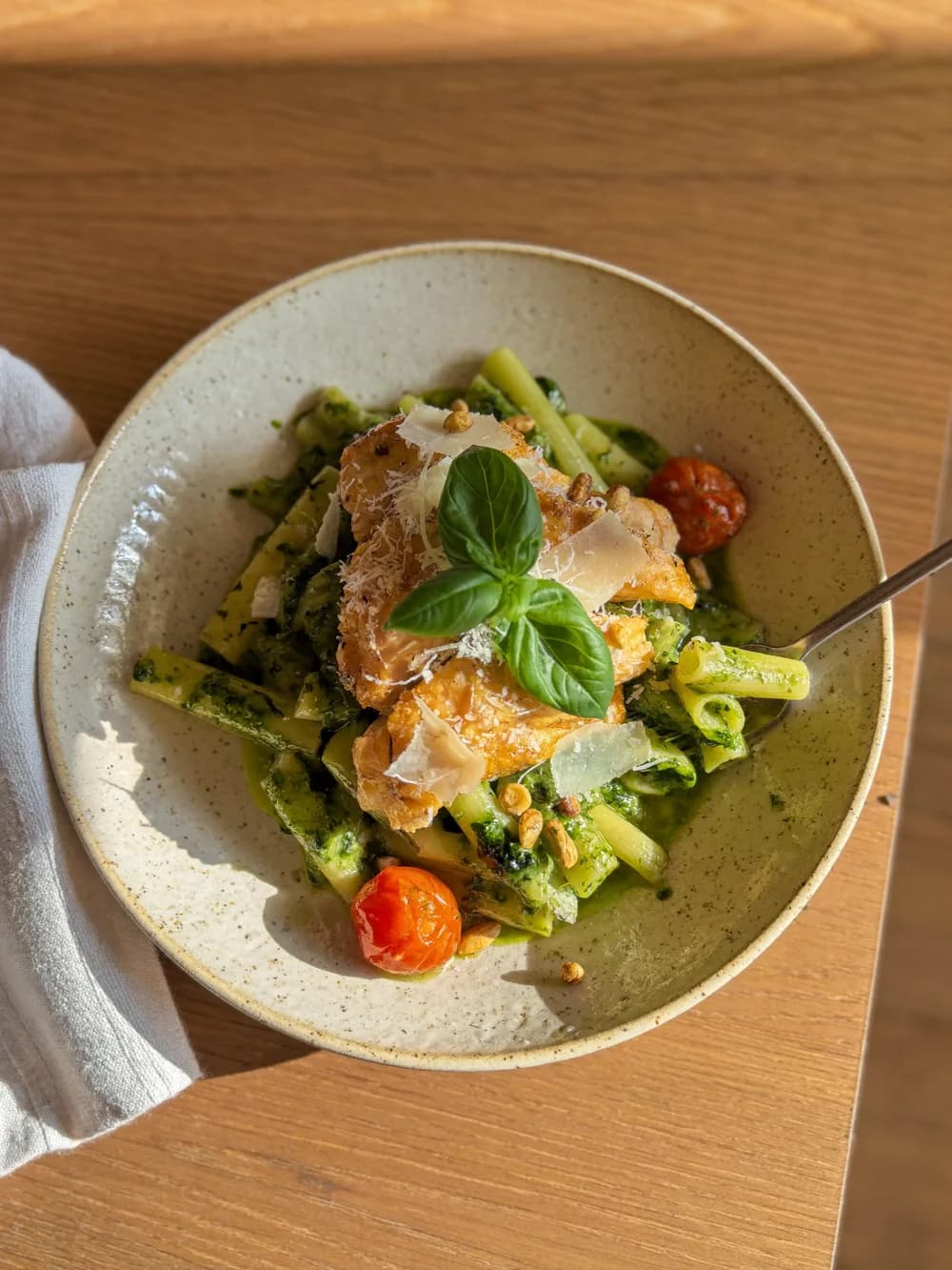 Creamy pesto chicken pasta in a speckled bowl